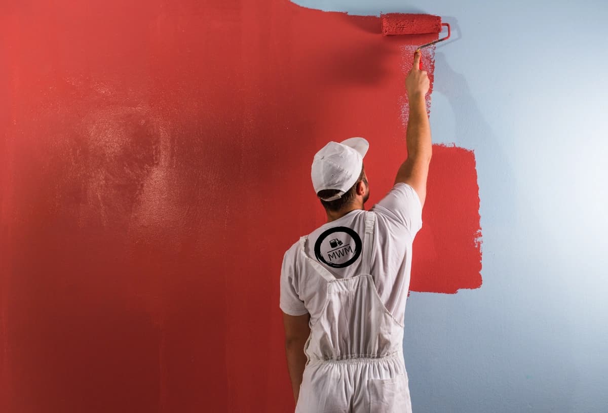 A painter painting a wall red.